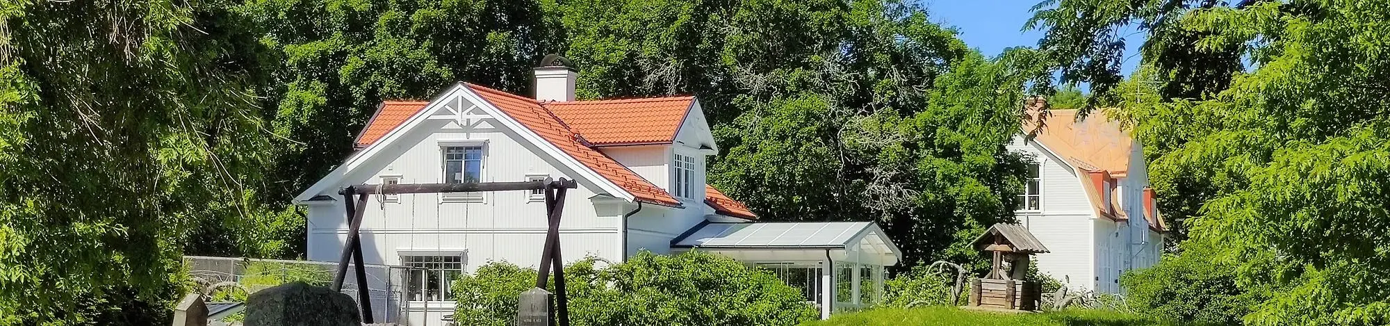 Vita hus med röda tegeltak bland grönskan - Östervåla