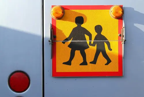 Skolskjutsskylt med två barn som håller varandra i handen