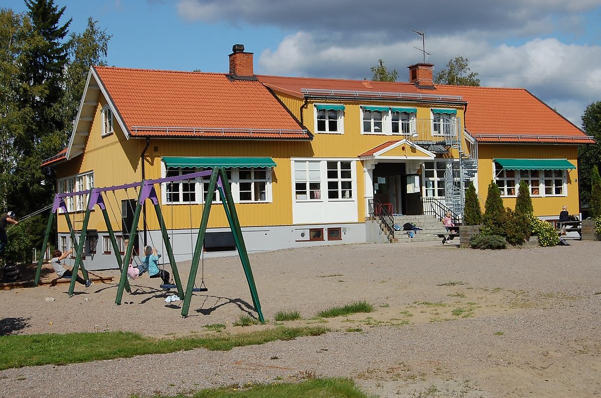 Vittinge skola. En gul gammeldags skolbyggnad i sommarmiljö.