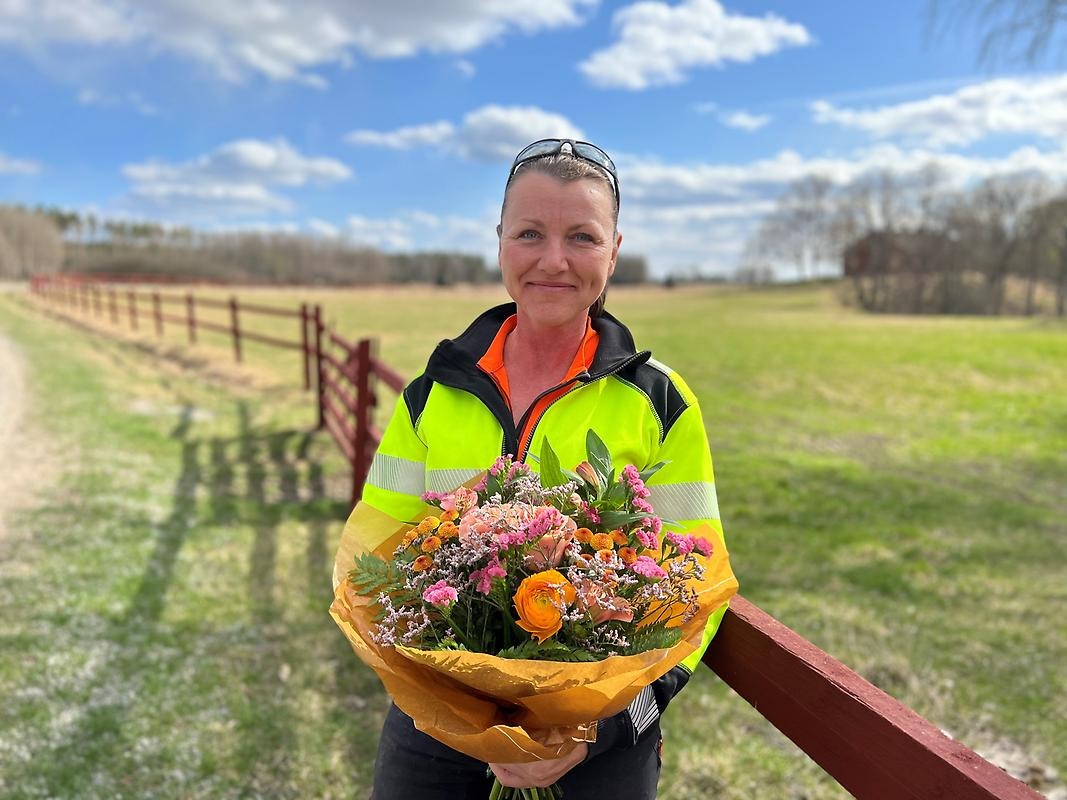 Årets Företagare 2022 Ann Elisabeth Jacobsen håller en bukett blommor i lantlig miljö.