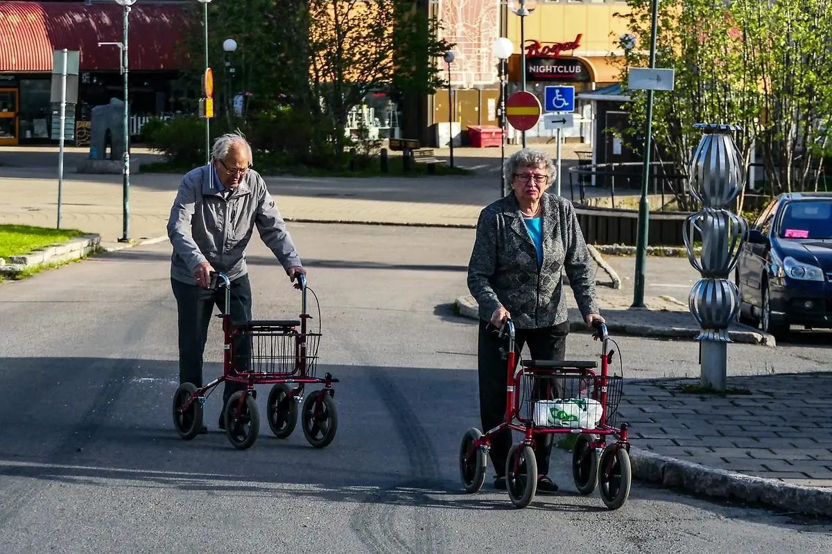 Äldre man och kvinna går över gatan med rollatorer