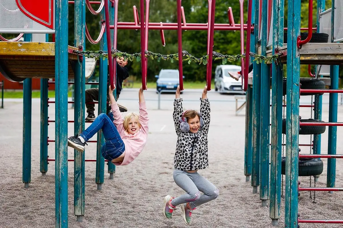 Två flickor leker på skolgårdens klätterställning