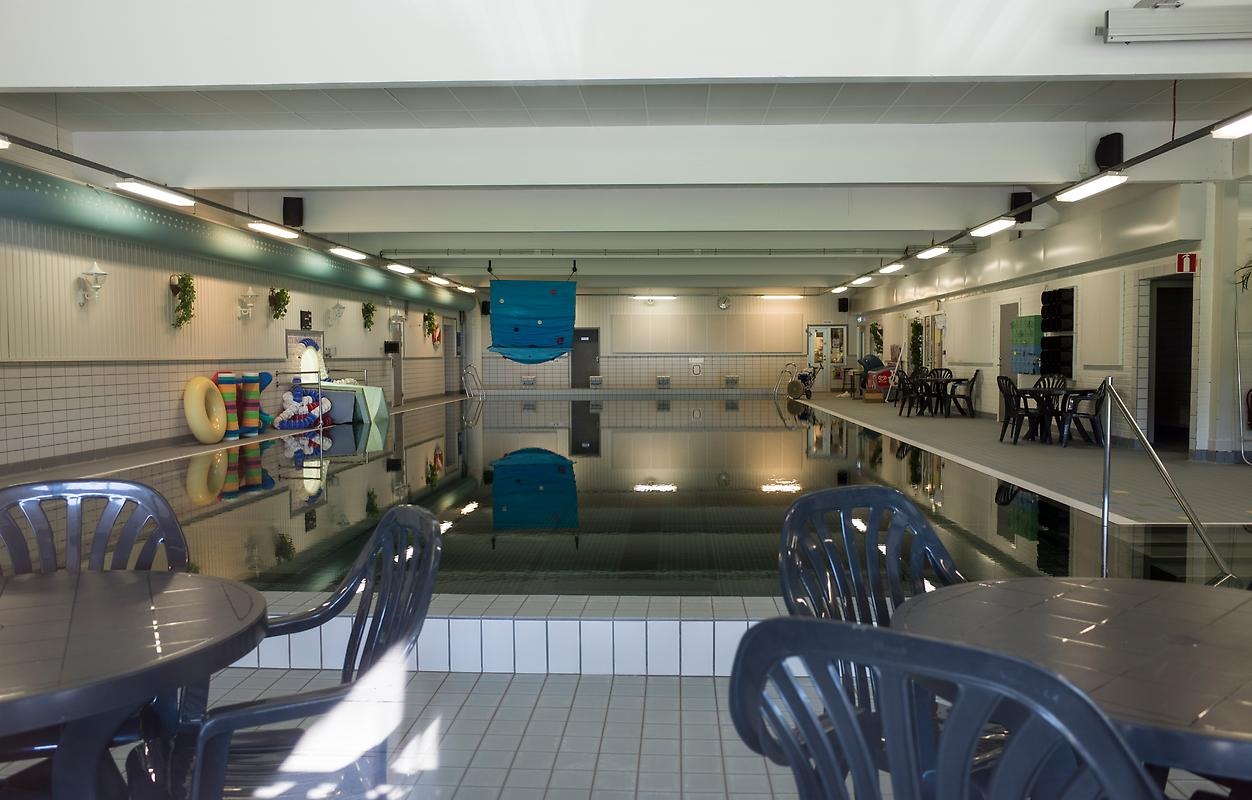 Stora simbassängen i Heby Arena med bord och stolar på bassängkanten.
