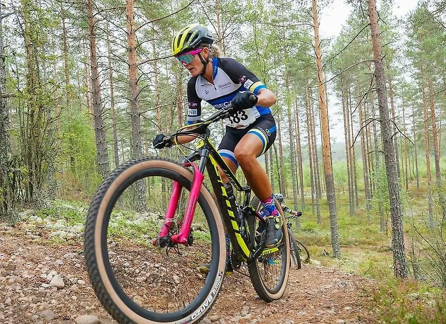 Kvinna cyklar mountainbike i skogen 