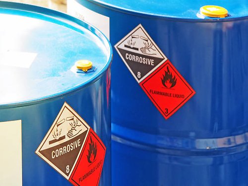 Blåa tunnor med giftigt avfall med gula varningsetiketter.