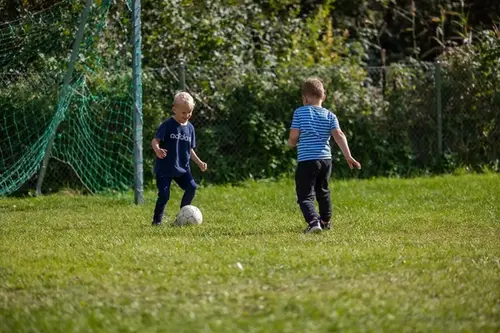 Två pojkar spelar fotboll på gräsplan