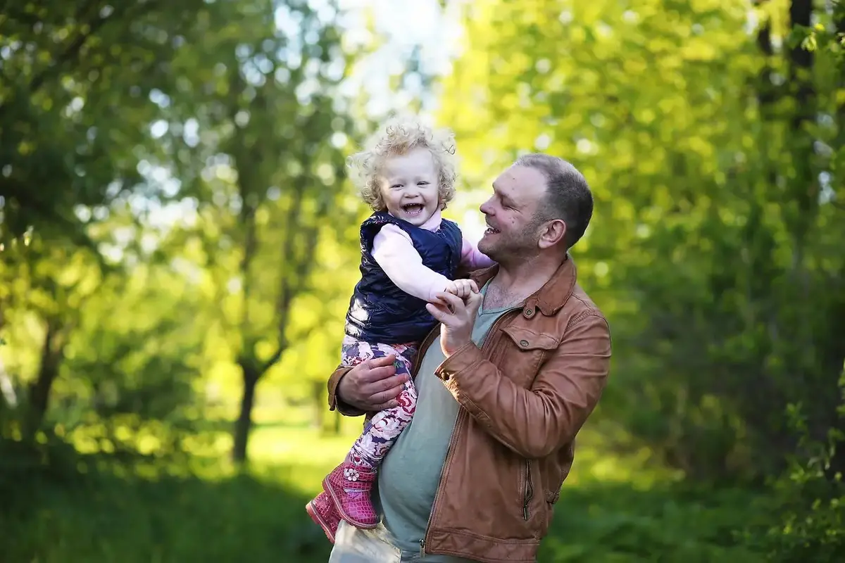 Flicka med sin pappa i en park på våren
