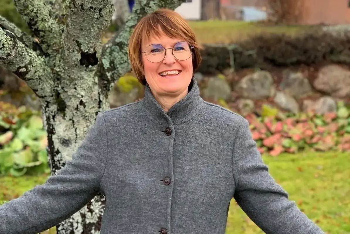 Glad kvinna utomhus med utsträckta armar mot kameran, förvaltningschef Åsa Nylander