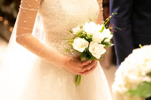 Kvinna i brudklänning med blommor i händerna