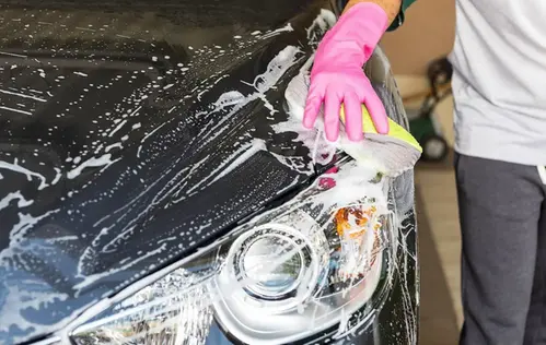 Person tvättar bilen med rosa plasthandskar på