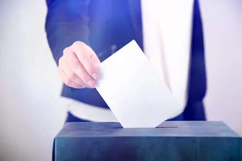 Kvinna lägger röstsedel i låda