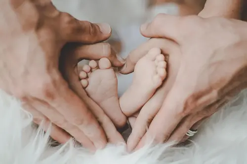 Bebisfötter med händer formade som hjärta omkring dem