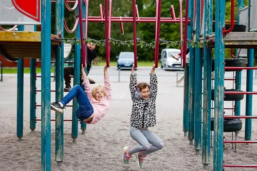 Två skolflickor leker vid en klätterställning ute på skolgården